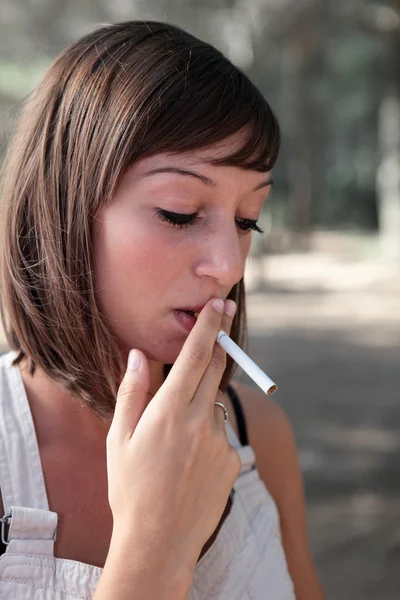 Açık havada bir sigara aydınlatma oldukça genç bir kadın portresi — Stok fotoğraf