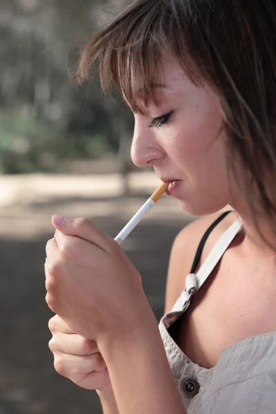 Açık havada bir sigara aydınlatma oldukça genç bir kadın portresi — Stok fotoğraf