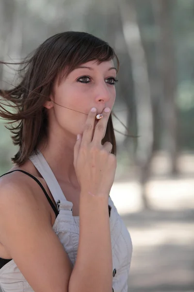 Porträtt av en ganska ung kvinna tända en cigarett utomhus — Stockfoto