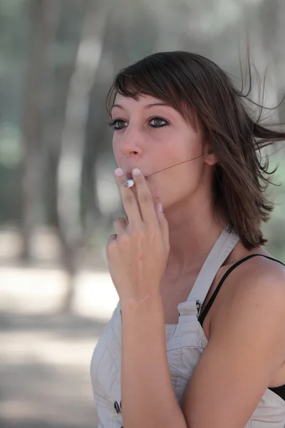一个年轻漂亮的女人户外照明一支香烟的肖像 — 图库照片