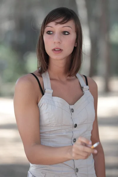 Portrait d'une jolie jeune femme allumant une cigarette à l'extérieur — Photo