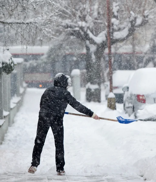 Mujer paleando nieve de una acera después de una fuerte nevada en una — Foto de Stock