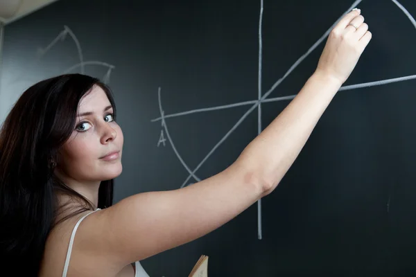 Hübsche junge Lehrerin zeichnet auf der Tafel — Stockfoto