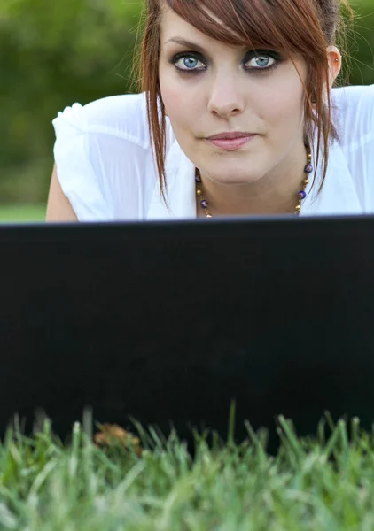 Mooie jonge vrouw liggen op het gras - met behulp van haar laptop compute — Stockfoto