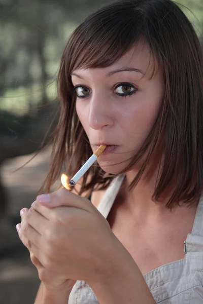 Portret bardzo młoda kobieta, oświetlenie papierosa na zewnątrz — Zdjęcie stockowe
