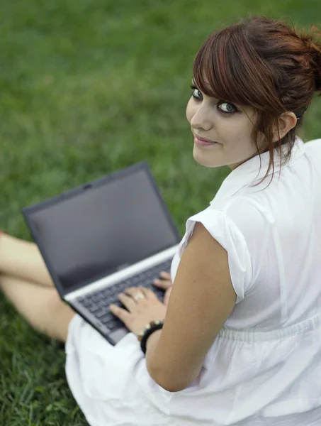 Mooie jonge vrouw die werkt op een laptopcomputer buitenshuis — Stockfoto