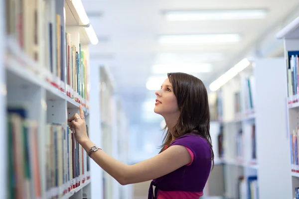 Hübsche junge College-Studentin in einer Bibliothek — Stockfoto