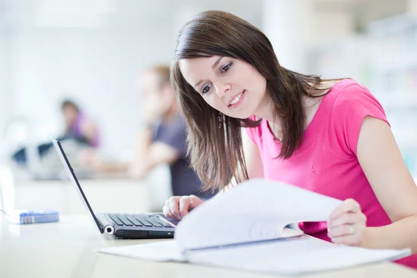 In the library - pretty female student with laptop and books wor — Stock Photo, Image