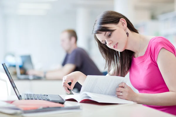 In de bibliotheek - vrij vrouwelijke student met laptop en boeken wor — Stockfoto