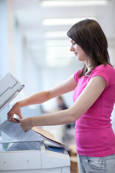 Pretty young woman using a copy machine — Stock Photo, Image