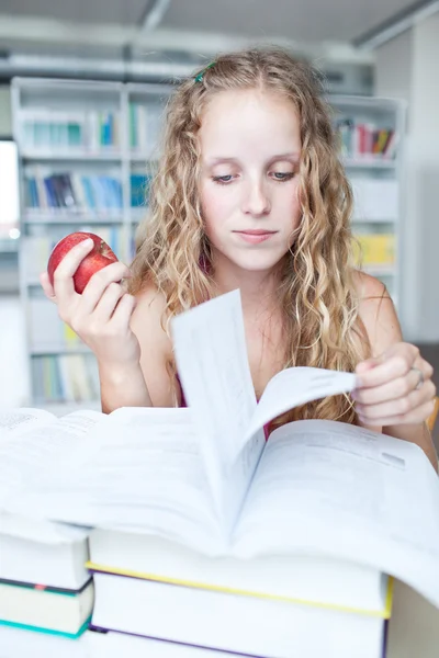 Estudiante universitaria bastante femenina en una biblioteca (DOF poco profundo; color t — Foto de Stock