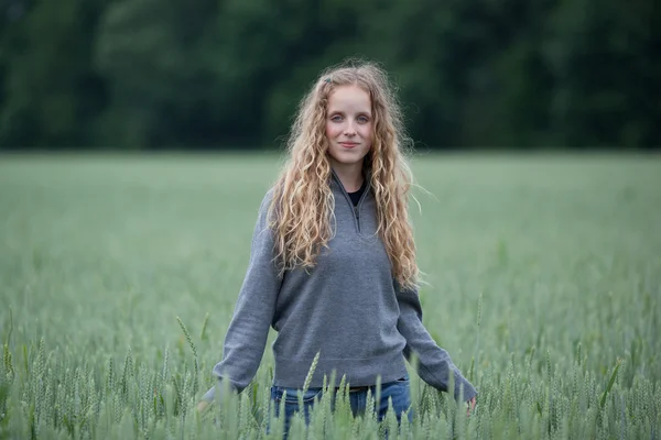 Retrato de una hermosa joven de pie en un campo verde - loo —  Fotos de Stock