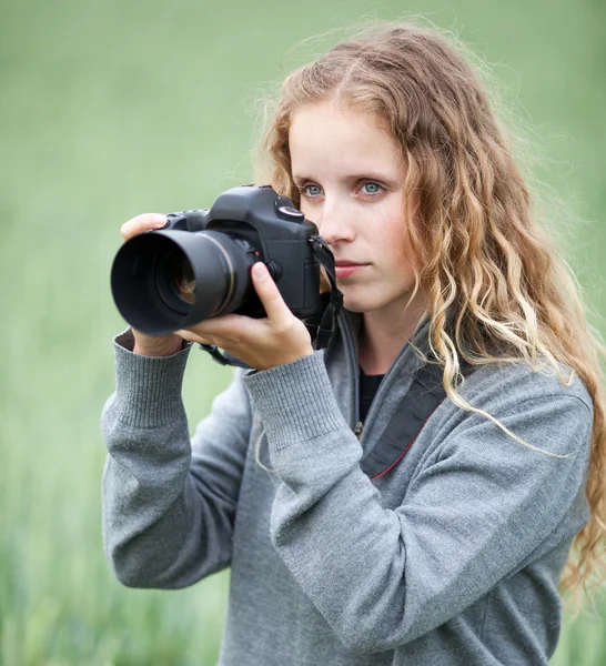 Mujer bastante joven con una cámara réflex digital al aire libre tomando fotos —  Fotos de Stock