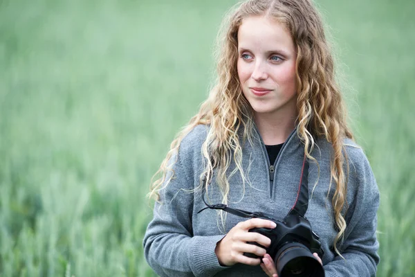Симпатичная молодая женщина с фотоаппаратом DSLR на улице, делающая снимки — стоковое фото