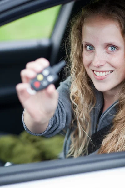 Hübsche junge Frau zeigt ihr nagelneues Auto — Stockfoto