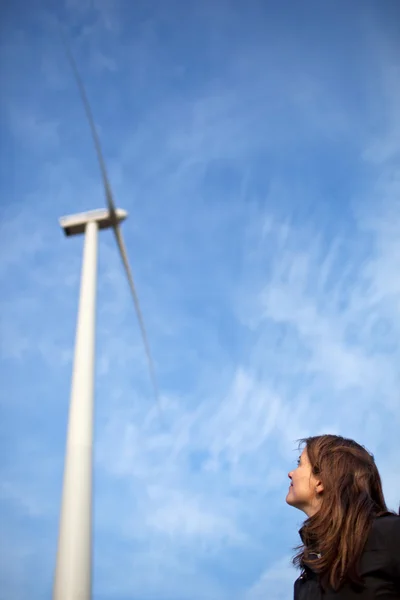 Muito jovem olhando para um moinho de vento / turbina eólica girando no w — Fotografia de Stock