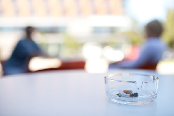 Skoking in public places concept - close-up of an ashtray on a t