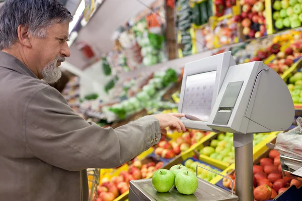 Knappe senior man winkelen voor vers fruit in een supermarkt — Stockfoto