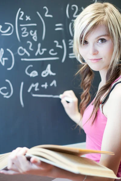 Красивая молодая студентка колледжа пишет на доске — стоковое фото