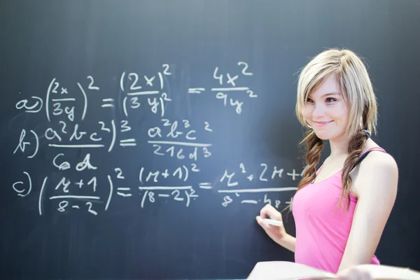 Hezká mladá studentka psaní na tabuli — Stock fotografie