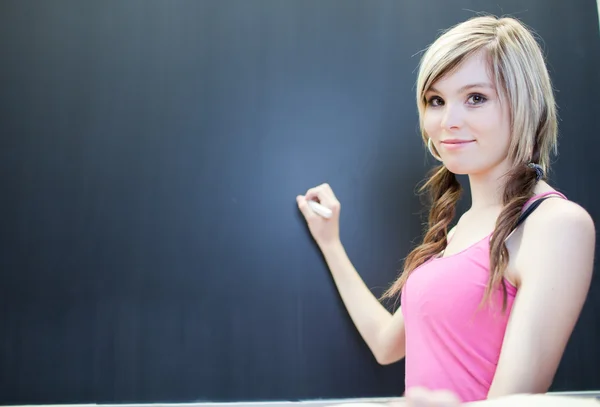 Hübsche junge Studentin schreibt auf der Tafel — Stockfoto