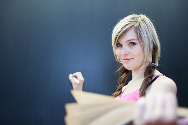 Красивая молодая студентка колледжа пишет на доске — стоковое фото