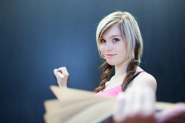 Hübsche junge Studentin schreibt auf der Tafel — Stockfoto