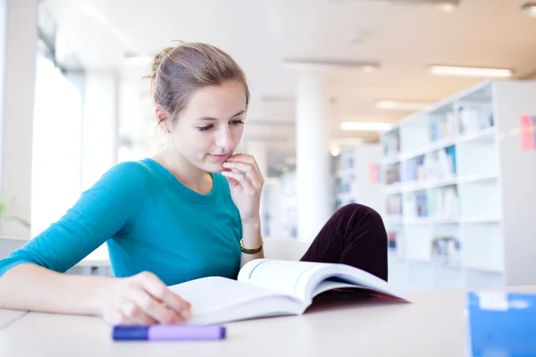 Ganska unga collegestudent i ett bibliotek — Stockfoto