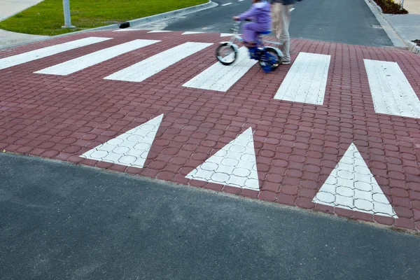 Father with a small girl on a bike crossing a street (motion bl — Stock Photo, Image