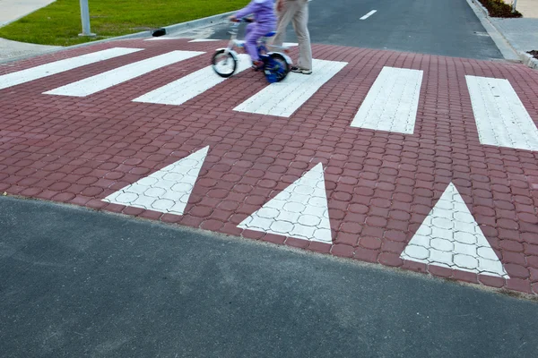 Father with a small girl on a bike crossing a street (motion bl — Stock Photo, Image