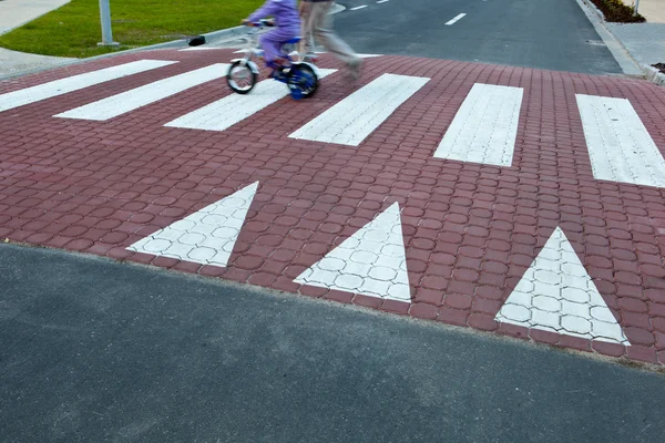 Far med en liten tjej på en cykel som korsar en gata (motion bl — Stockfoto