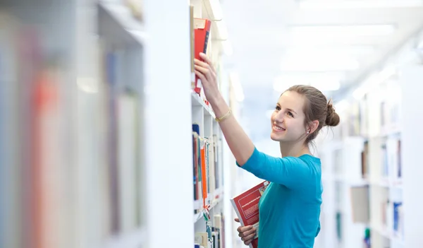 Красивая молодая студентка в библиотеке — стоковое фото