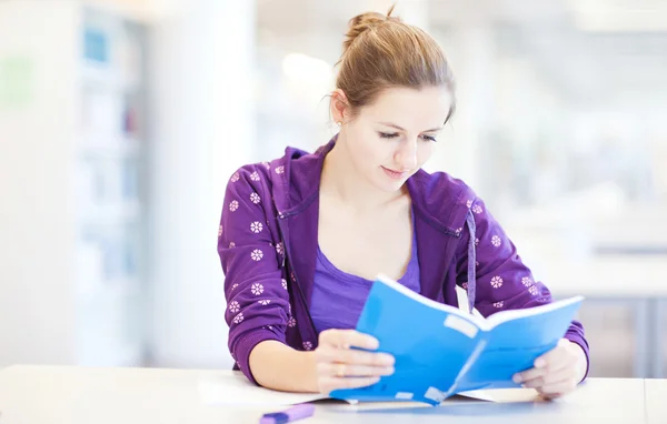 Estudiante universitario bastante joven en una biblioteca (DOF poco profundo; color a — Foto de Stock