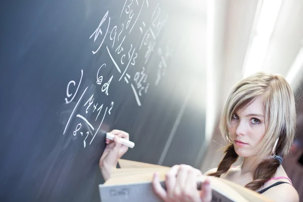 Pretty young college student writing on the chalkboard Royalty Free Stock Photos