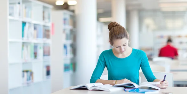 Pretty young college student in a library Royalty Free Stock Photos