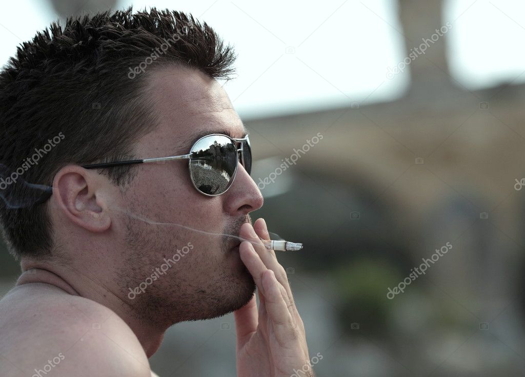 Deadly nasty habit - Male smoker wearing sunglasses smoking a ci