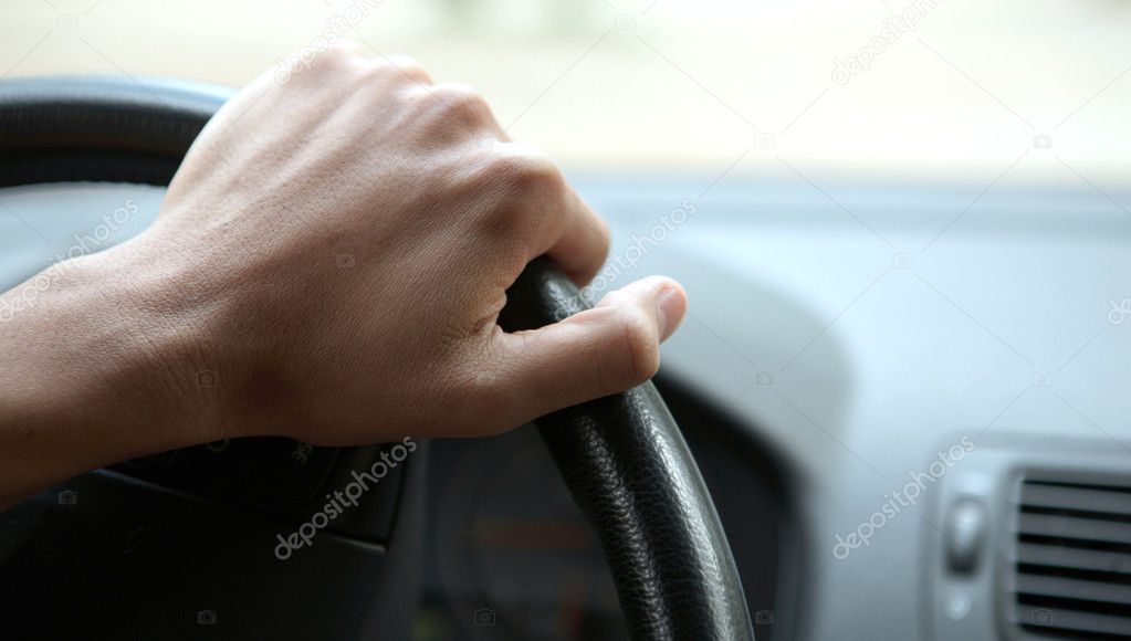 Close-up of a male hand on steering wheel in a modern car in the