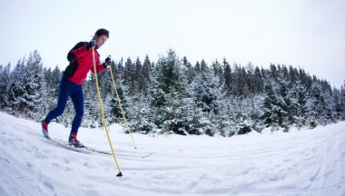 Young man cross-country skiing on a snowy forest trail clipart