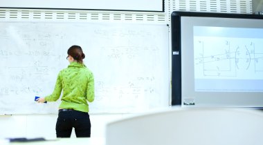 Young female college student in front of a whiteboard during a m clipart