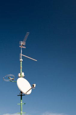 Antennas and a satellite dish on a roof clipart