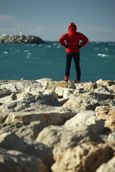 Молода жінка стоїть на кам'янистому березі — стокове фото