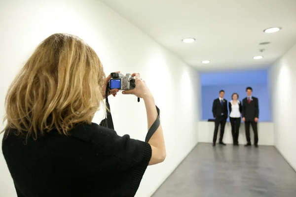 Mujer joven tomando una foto de sus tres colegas en un s formal —  Fotos de Stock