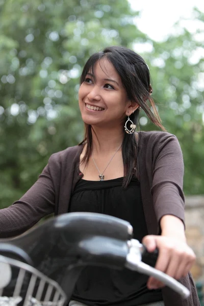 Mujer joven en una bicicleta al aire libre sonriendo — Foto de Stock