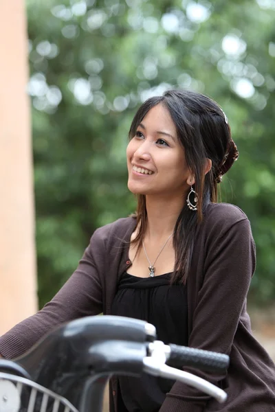 Jovem mulher em uma bicicleta ao ar livre sorrindo — Fotografia de Stock