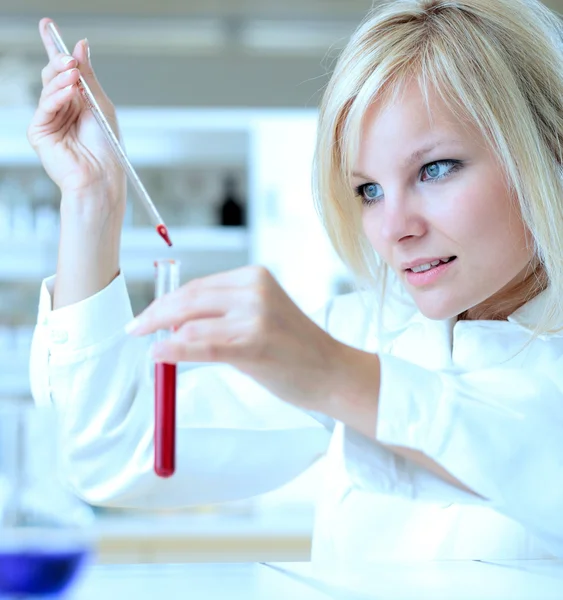 Close-up van een vrouwelijke onderzoeker bedrijf in een reageerbuis en een reto — Stockfoto