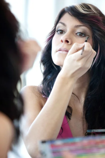 Pretty young woman applying mascara /eyeshadows in front of a mi — Stock Photo, Image