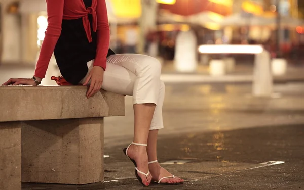 Bonita jovem mulher sentada em uma rua da cidade noite — Fotografia de Stock