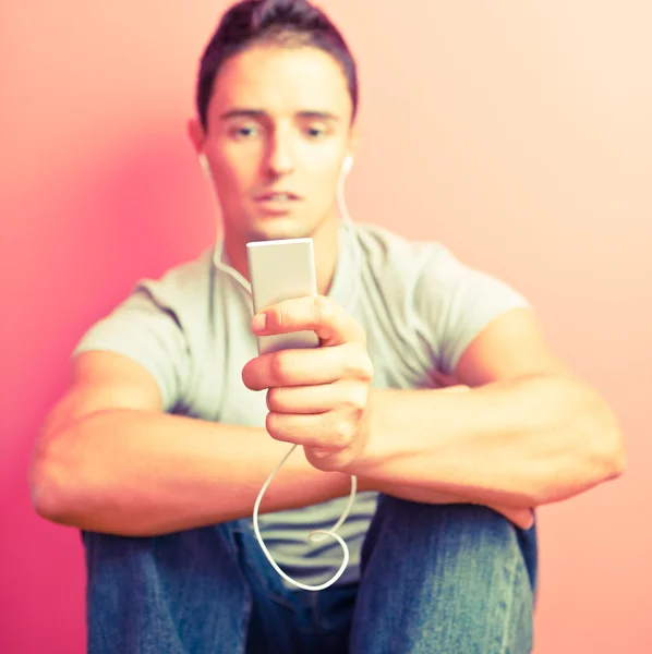 Mladý pohledný muž poslouchá hudbu na své přenosné mp3 pl — Stock fotografie