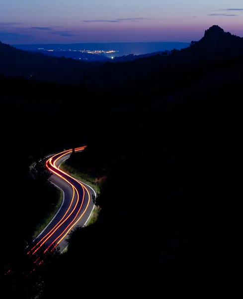 Carretera de montaña por la noche con los coches en movimiento rápido (imagen tonificada en color ) — Foto de Stock
