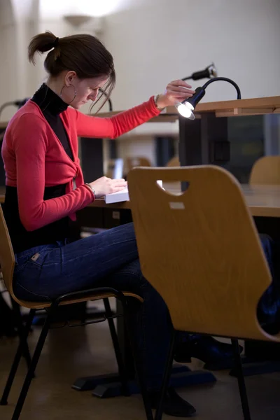 Ganska kvinnliga collegestudent i ett college bibliotek — Stockfoto
